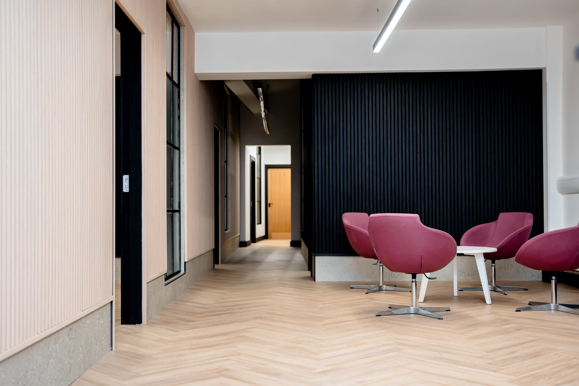 Lounge seating at Workpoint with pink armchairs against a slatted wood wall