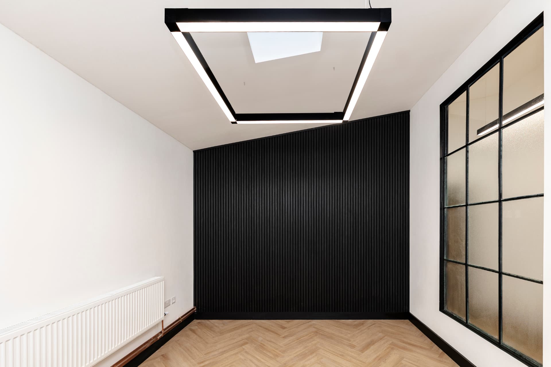 Small private office at Workpoint with black slatted feature wall, feature ceiling lighting and herringbone flooring