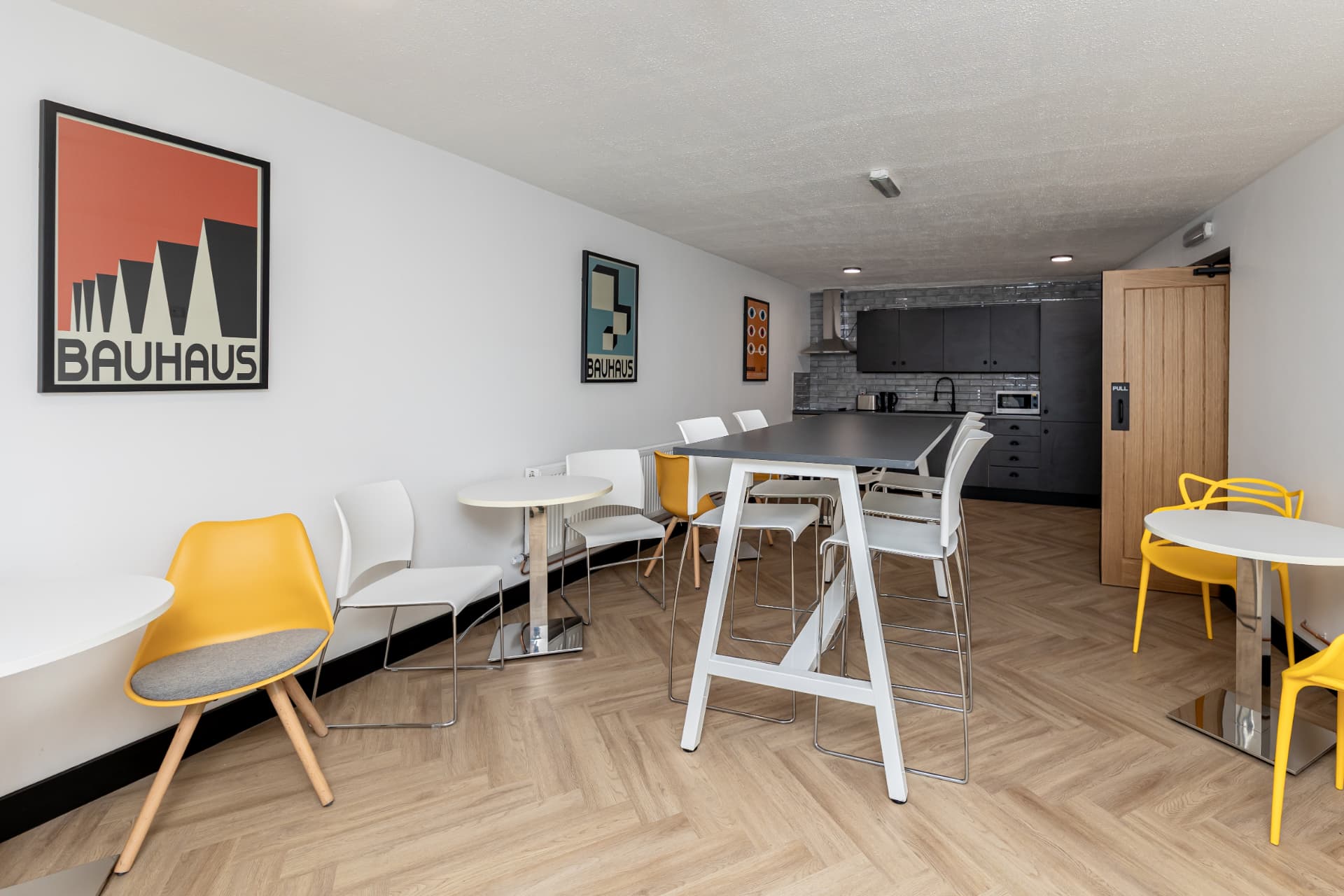Breakout and kitchen area at Workpoint with high tables and yellow bar stools